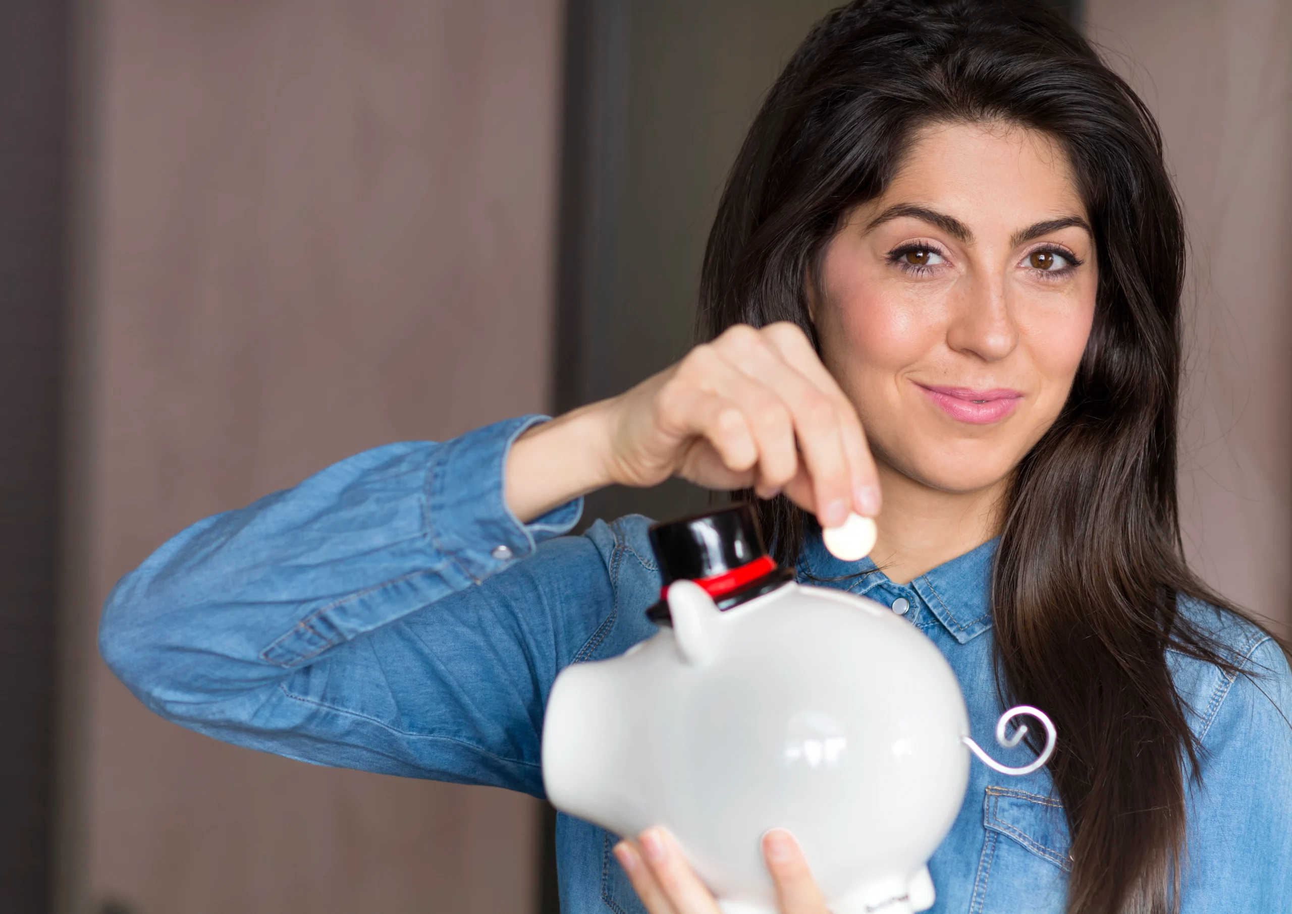 Smiling woman holding a piggy bank representing an investment account.
